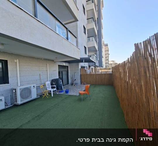 גדר במבוק ודשא סינתטי בחצר בניין מגורים